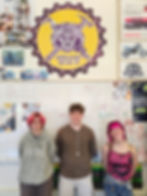 3 students posing in front of Wildcat school logo