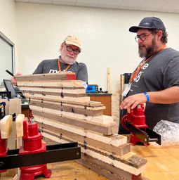 tool techs chris and luke standing by a stack of wood