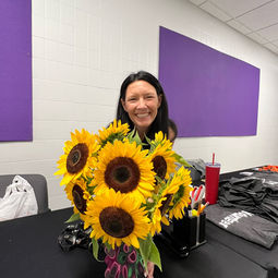 amy gray standing behind a vase of sunflowers