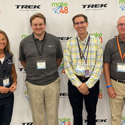 four vips standing together in front of the trek step and repeat banner