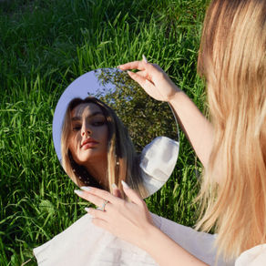A young women holds a mirror that shows her reflection
