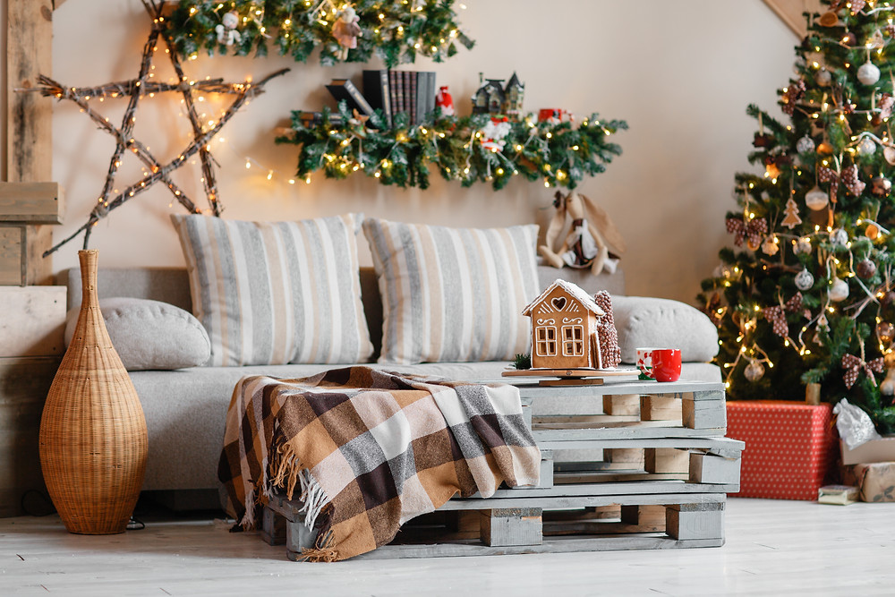home interior decorated for christmas with a tree, gingerbread house and white lights