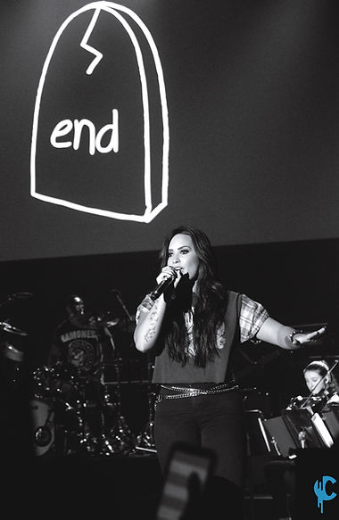 Demi Lovato singing on stage in a black and white photo