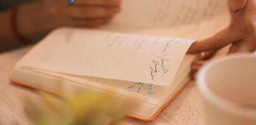 Close-up of hands writing in a journal, representing the reflective work of therapy for relationships after having a baby