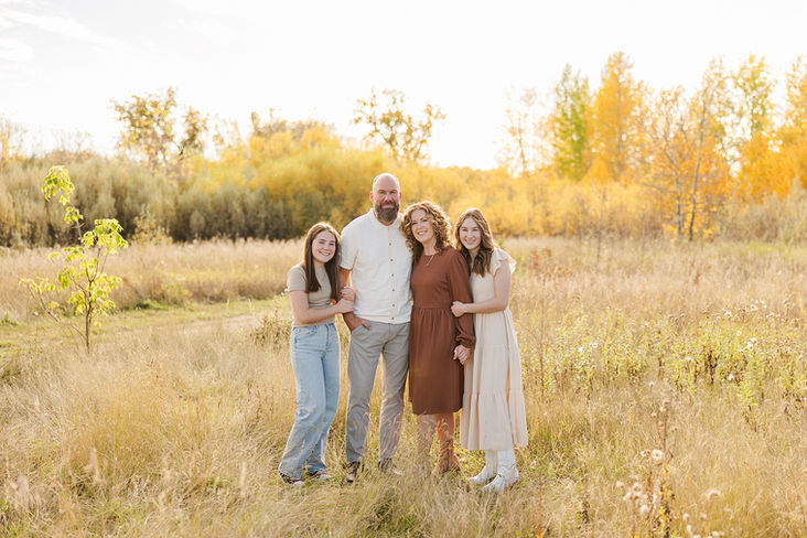 Family standing in field with fall leaves