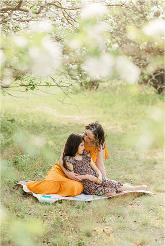 Mom and daughter sitting together with blossoms around