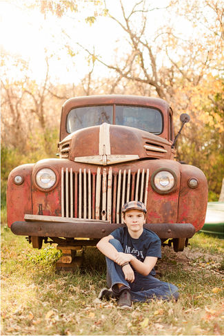teenage boy sitting infront of old truck