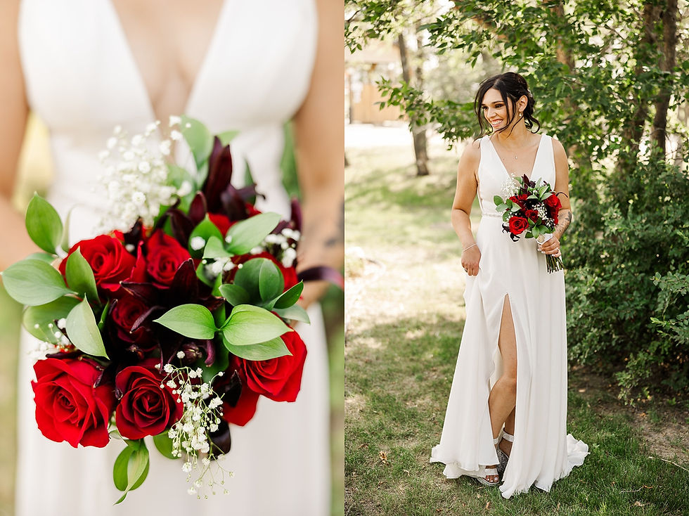Bride in a white dress holding a bouquet of red roses and greenery, standing on grass with trees in the background, smiling.