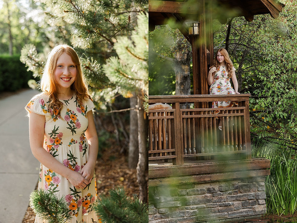 Red-haired woman in a floral dress smiles by pine trees and sits on a wooden porch in a lush garden, with sunlight creating a warm glow.