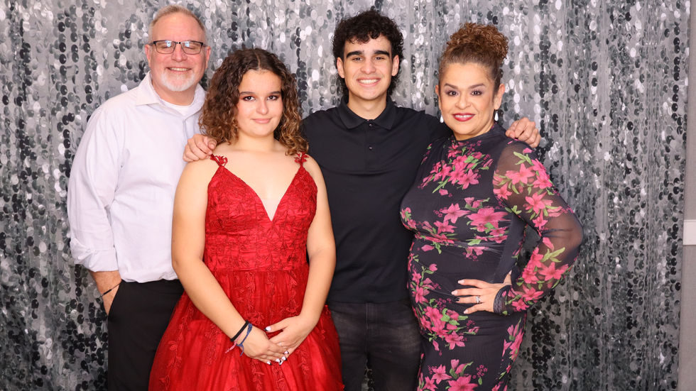 Four people posing in front of a sparkly backdrop.