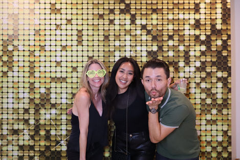 Three people posing in front of a gold backdrop.