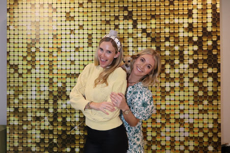 Two people smiling in front of a golden backdrop.