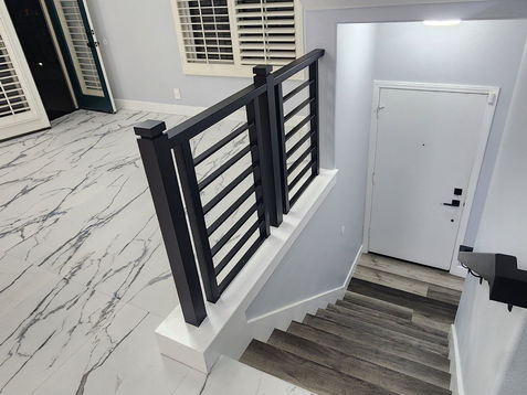 Modern staircase with marble flooring and sleek railing.