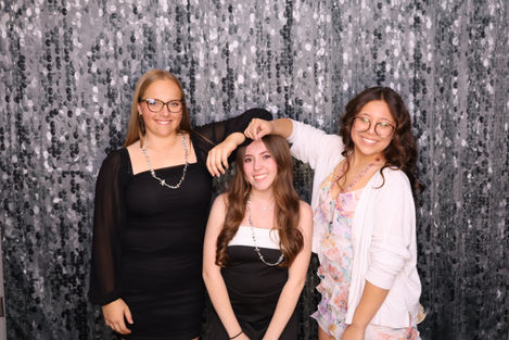 Three people posing in front of a sparkly backdrop.