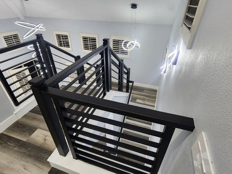Modern staircase with black railings and wooden steps.