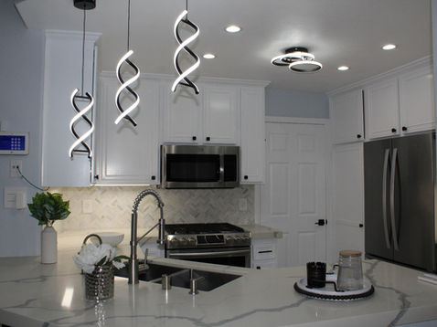 Modern kitchen with spiral pendant lights and stainless appliances.