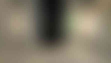 Contemporary living room with white marble-look flooring, a sleek black fireplace, and window shutters.