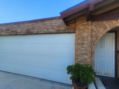 Brick house with garage and potted plant outside.