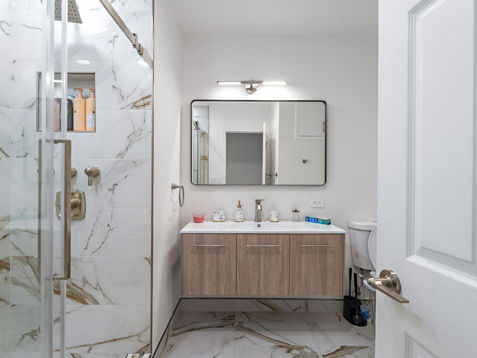 Modern bathroom with marble accents and wooden vanity.