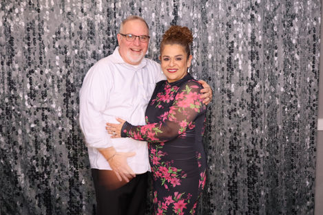 A couple posing in front of a glittery backdrop.