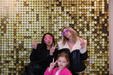 Three people posing with peace signs, gold sequin backdrop.