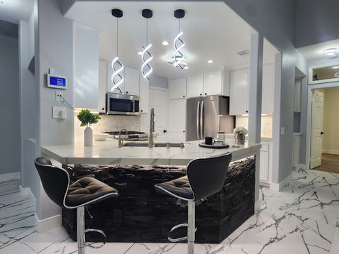 Modern kitchen with island and stylish lighting fixtures.