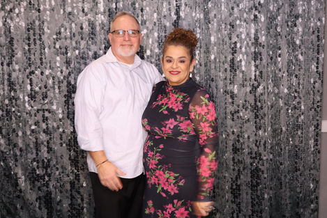 A couple posing in front of a glittery backdrop.