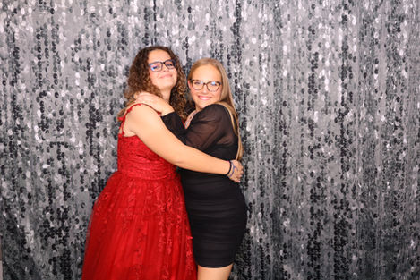 Two people hugging in front of a sparkly backdrop.