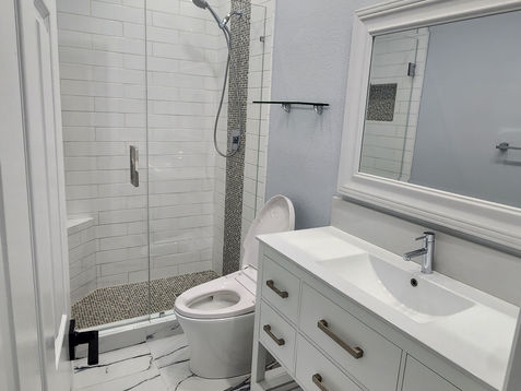 Modern bathroom with glass shower and white vanity.