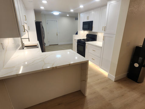 Modern kitchen with white cabinets and marble countertops.