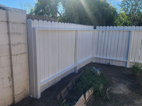 White fence with sunlight and garden area.