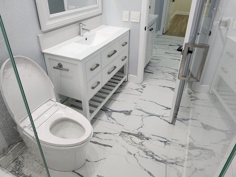 Modern bathroom with marble floor and white fixtures.