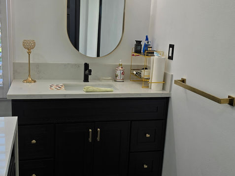 Bathroom vanity with oval mirror and gold accents.