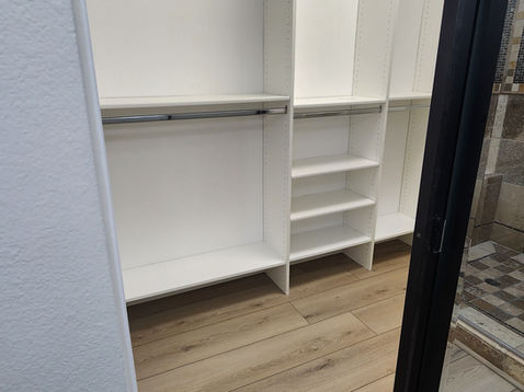 Empty white closet with wooden floor.