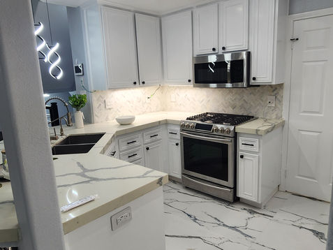 Modern kitchen with white cabinets and marble flooring.