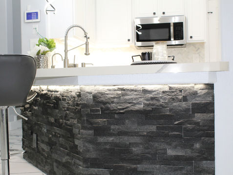 Modern kitchen with stone island and stainless steel appliances.