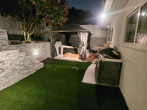 Nighttime backyard with gazebo and artificial grass.