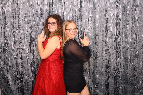 Two people posing playfully in front of a sparkly backdrop.