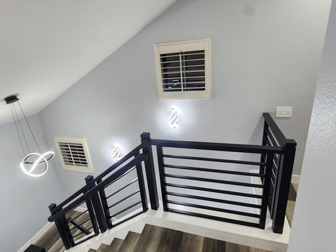 Black railing on staircase with gray walls.