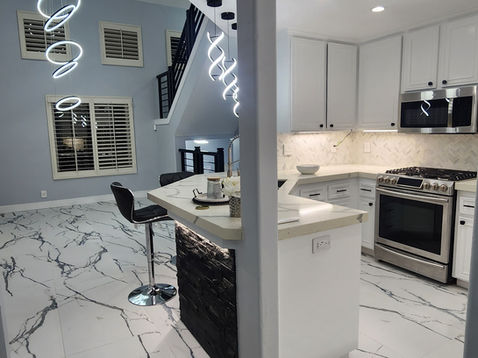 Modern kitchen with marble floor and sleek lighting.