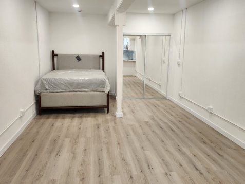 Minimalist bedroom with wooden flooring and white walls.