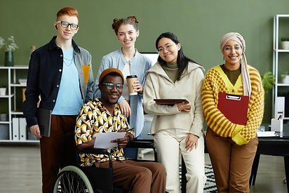Portrait of diverse creative team looking at camera with cheerful smiles while posing in o