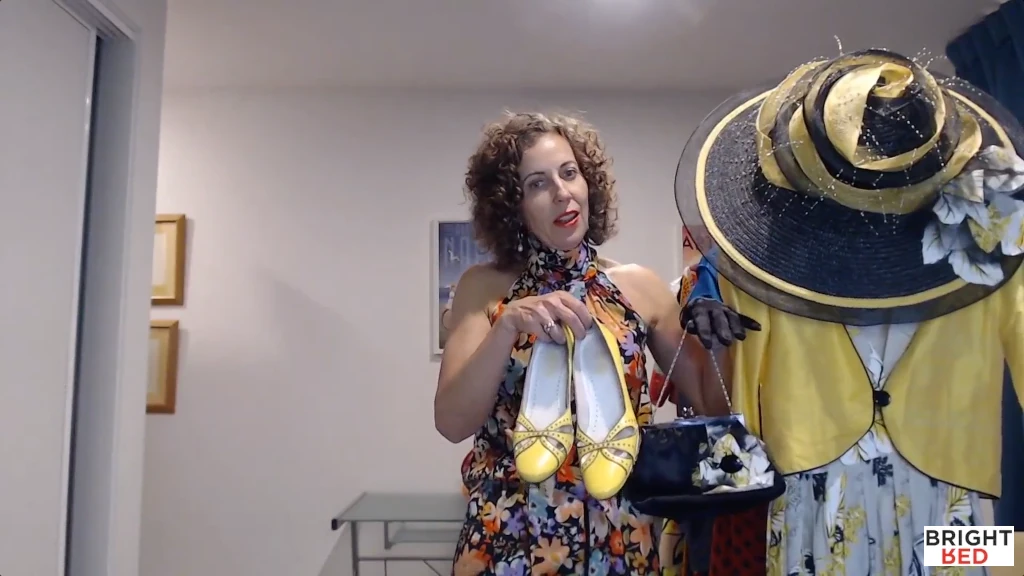 Stephanie Rumble displaying outfit with yellow shoes, gloves, hat, bolero jacket, and floral dress.