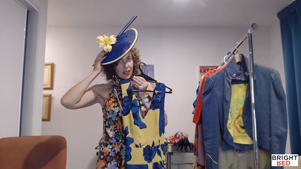 Stephanie Rumble wearing a fascinator while holding the jumpsuit.