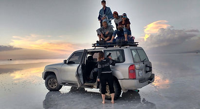 A group and a jeep reflected on the Bolivian salt flats
