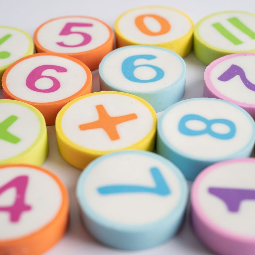Colorful plastic number tiles with digits and plus sign scattered on a white background, like a playful math set