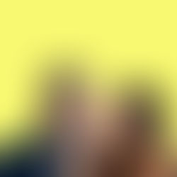 Woman whispers to surprised man in suit against a bright yellow background, creating a playful, secretive mood.