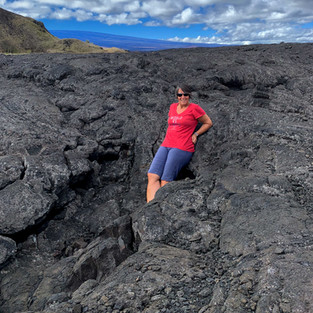 Woman in pink shirt standing on lava flow on big island of Hawaii