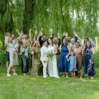 A joyful moment from a same-sex micro wedding, featuring a couple in elegant attire. They are surrounded by intimate, natural settings or a small, personal ceremony setup. The focus is on the couple's connection and love, with soft lighting highlighting the intimate atmosphere