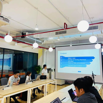 Người thuyết trình trước màn chiếu trong phòng họp.